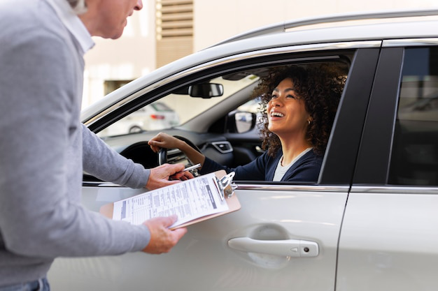 A person in a car talking to an auto agency professional