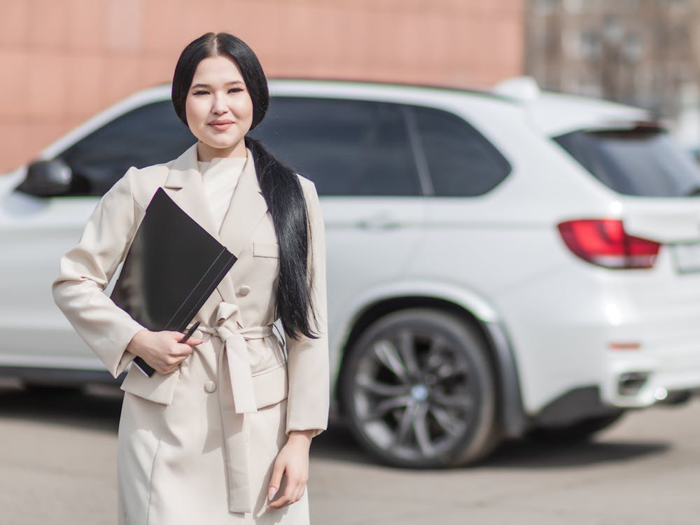 A person holding a folder with a car in the background