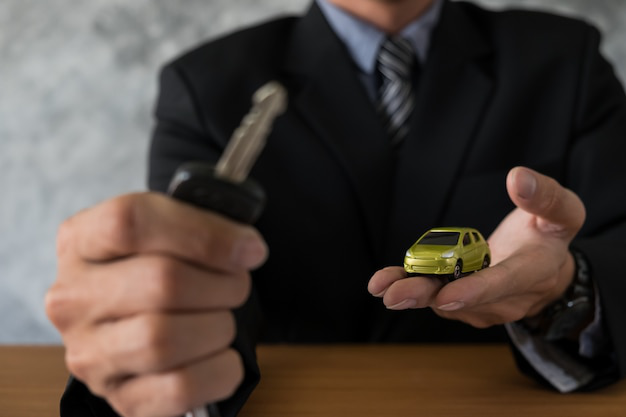 A person holding a miniature car and a key