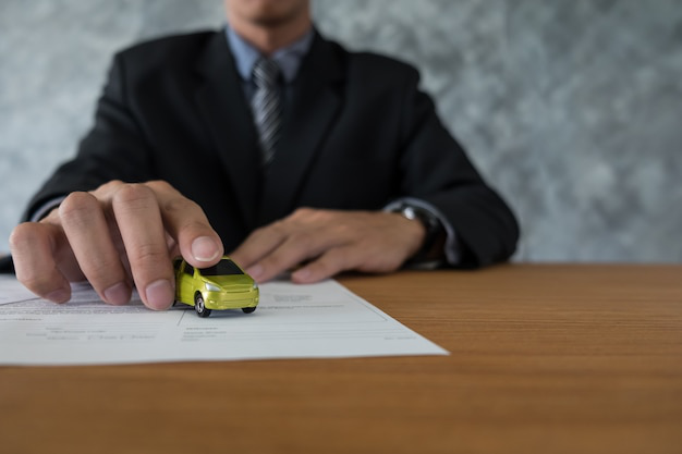 A person placing a miniature car on a paper