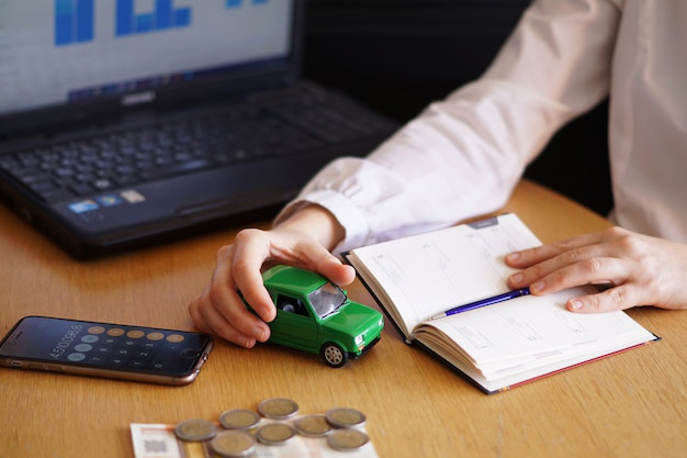 An auto tag agency professional holding a mini toy car and a notebook