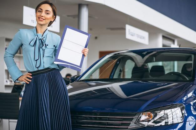 A person holding a file while standing next to a car