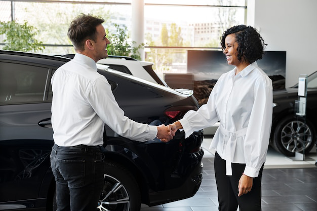 A auto title expert shaking hands with a car dealership manager