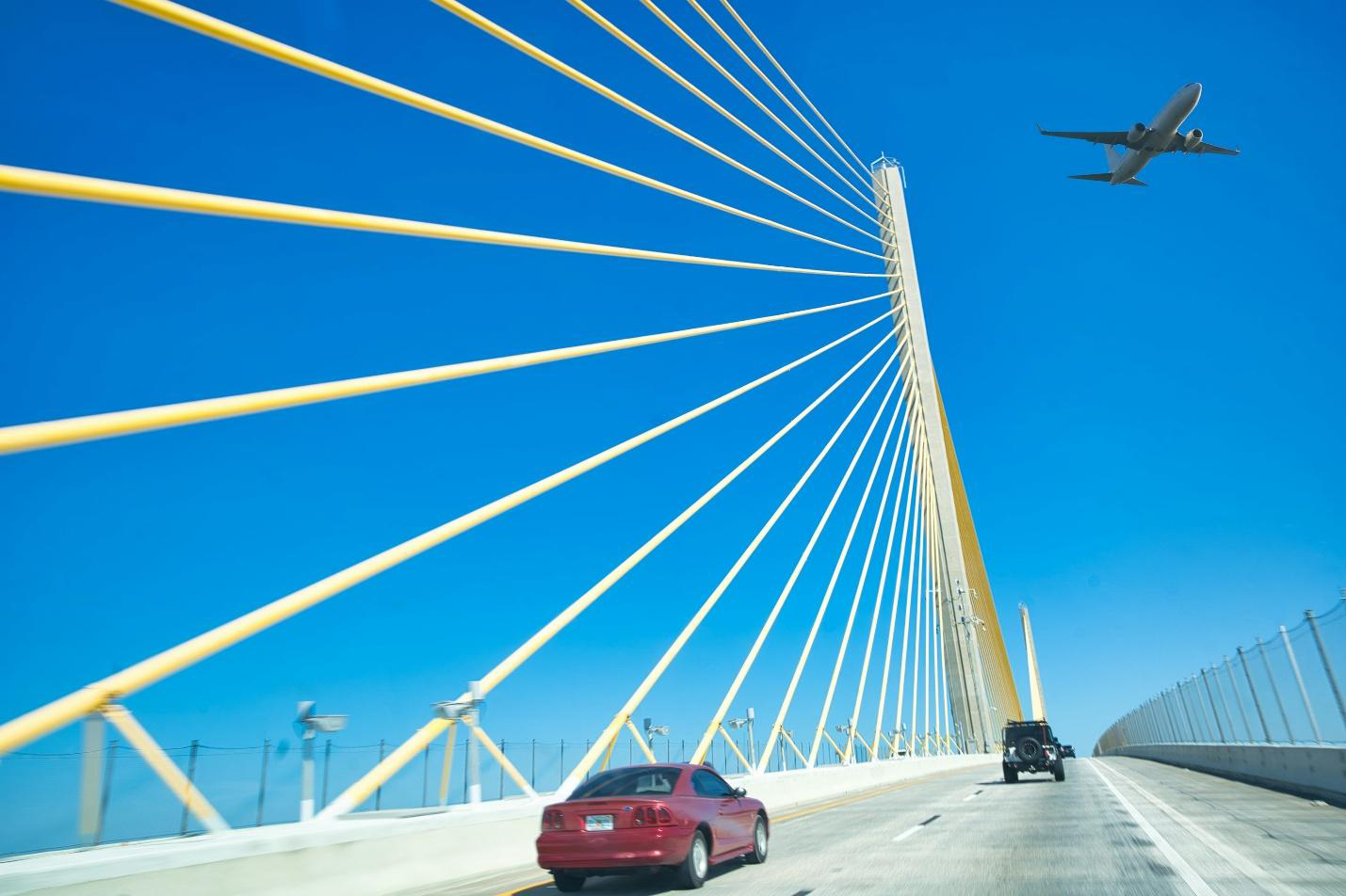 A red car driving across a bridge