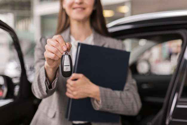 A person holding car keys and a file folder