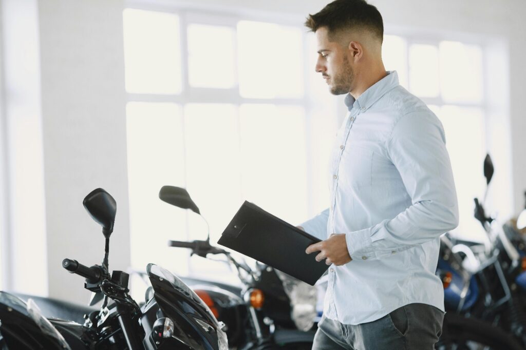 A person holding a file and looking at a motorbike