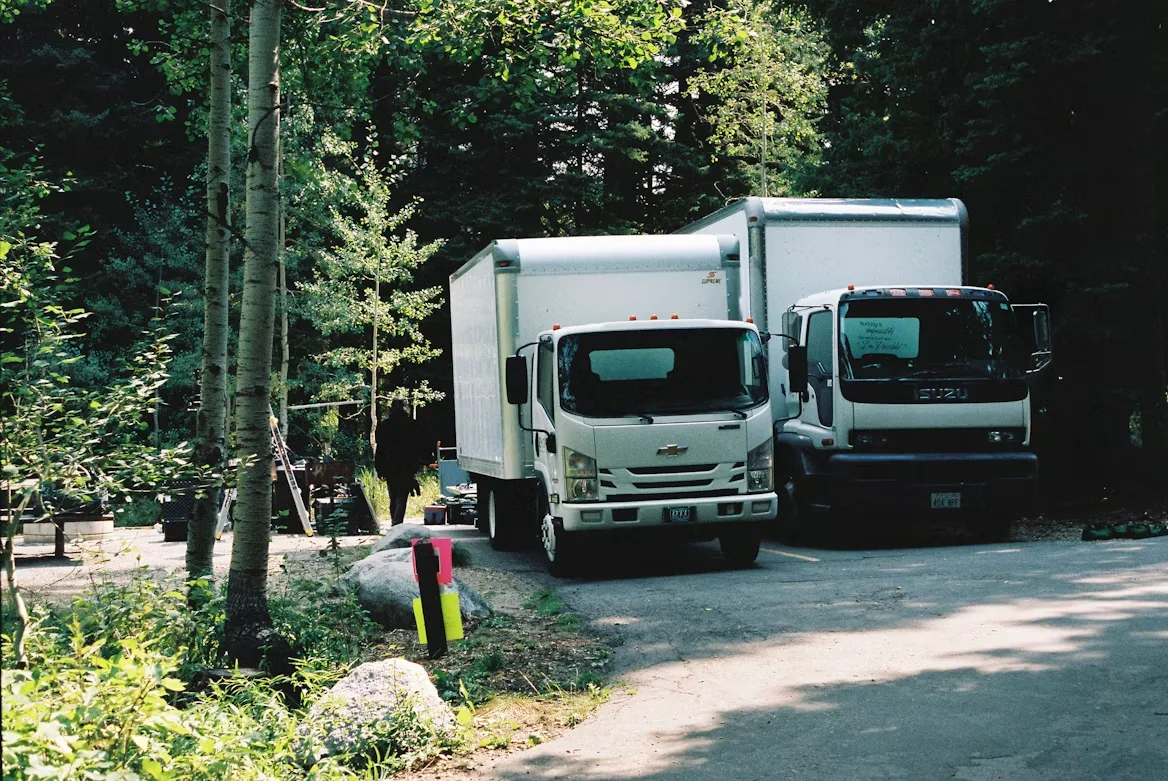 Two trucks on a road with trees